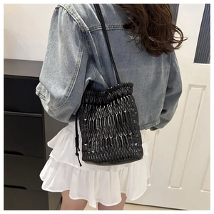Détail du sac seau noir plissé avec cordon de serrage et fine bandoulière en cuir