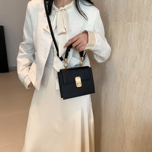 Elegant black square crossbody bag with gold lock shown with a chic tweed outfit