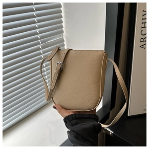 Macro shot of khaki pebbled leather shoulder bag with adjustable silver buckle strap