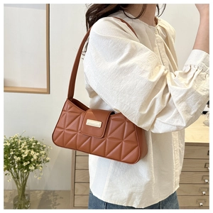 Bolso baguette marrón acolchado de estilo francés llevado al hombro por una modelo