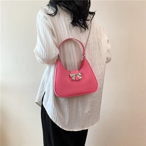 Borsa hobo rosa minimalista con fiocco argento e catena indossata da una modella