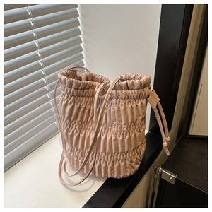 Détail d'un sac seau plissé rose avec fermeture à cordon et lumière naturelle douce