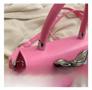Detailed view of pink crossbody bag featuring a large silver metallic bow and hardware