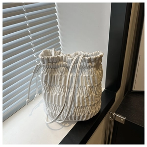 Vue détaillée du sac seau blanc matelassé avec une texture plissée élégante