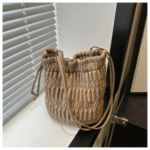 Détail du sac seau beige avec texture plissée verticale et fermeture à cordon pratique