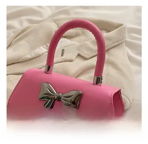 Detailed view of pink matte handbag with a large metallic silver bow and thick handle