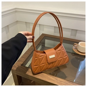 Detalle de bolso bandolera acolchado marrón con cierre dorado sobre una mesa de centro