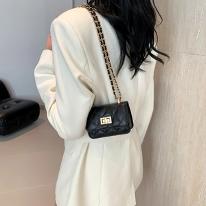 Classic black quilted crossbody bag with gold chain strap worn with a stylish blazer