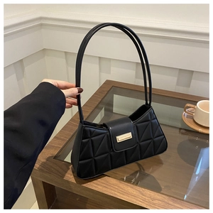 Detalle de bolso acolchado negro con hebilla dorada y costuras geométricas únicas