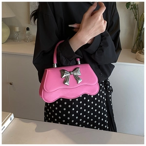 Pink handbag detail showing silver metal bow and wavy edge design on model
