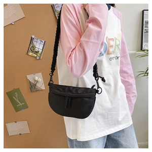 Detail view of black crescent crossbody bag with woven shoulder strap and dual zippers