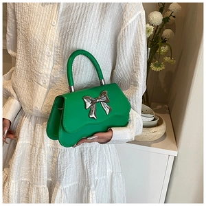 Close-up of vibrant green bow handbag with silver buckle and leather texture
