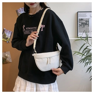 Detailed shot of a white crescent crossbody bag with thick woven shoulder strap on model