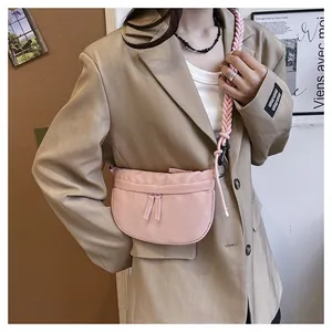 Pink nylon crescent crossbody bag with woven shoulder strap shown in a stylish side view