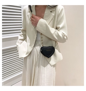 Detailed view of heart-shaped black PU leather crossbody bag with chain on a model