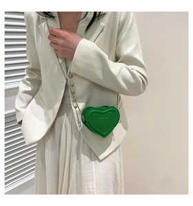 Detail of green heart chain bag showing quilted texture and delicate silver metal strap