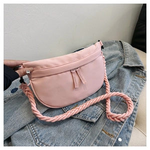 Detail of pink half-moon crossbody bag with woven rope strap on denim jacket