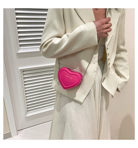 Close-up of a heart-shaped fuchsia mini bag with golden logo and silver chain strap