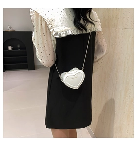 Rear view of a model wearing a white heart-shaped leather crossbody bag with chain strap