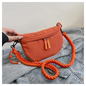 Detail of orange crescent bag featuring a thick braided rope strap on denim background