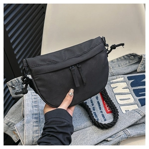 Detail of black crescent crossbody bag with woven rope strap and dual zip pockets