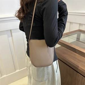 Minimalist large brown pebble leather crossbody bucket bag shown on a model side view
