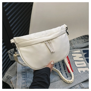 Detail of white half-moon crossbody bag featuring a thick woven rope shoulder strap