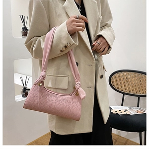 Pink crocodile pattern shoulder bag featuring a unique hand-knotted wide fabric strap detail