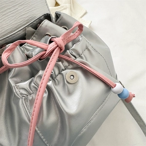 Gros plan détaillé d'un sac à dos argenté avec cordon rose et perles de décoration