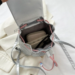 Vue de dessus du mini sac à dos argenté montrant l'intérieur avec portefeuille et lunettes