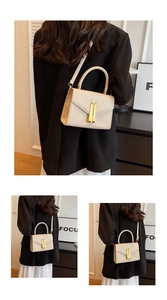 Detail of cream rectangular crossbody bag featuring a vertical gold metal clasp closure