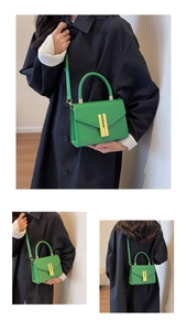 Detail view of emerald green leather crossbody bag showing metal buckle and handle