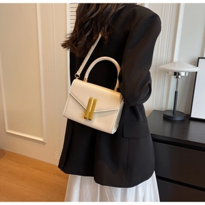 Close-up of beige leather crossbody bag featuring an elegant gold-tone metal lock buckle