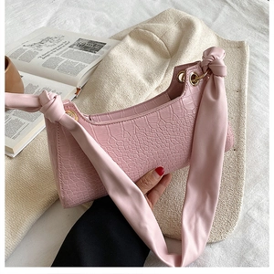 Detailed close-up of pink faux-crocodile skin bag with unique knotted shoulder strap