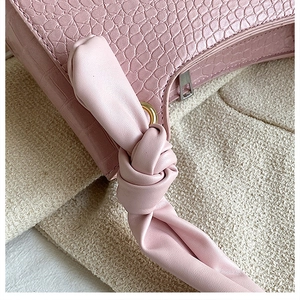 Close-up of pink faux crocodile skin texture and knotted shoulder strap detail