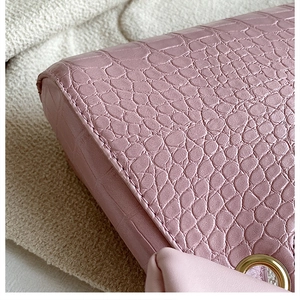 Close-up of pink faux crocodile skin texture and gold metal ring detail on the handbag