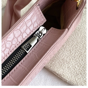 Detail of silver metal zipper and crocodile embossed texture on pink leather handbag