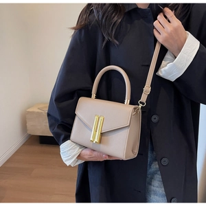 Detailed view of beige crossbody bag with gold metal clasp and leather texture