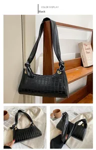 Detail view of black crocodile pattern faux leather handbag with knot strap and gold rings