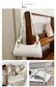 Detail of white crocodile pattern shoulder bag with a stylish knotted fabric strap