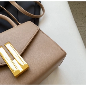 Detail of tan lychee grain leather handbag with gold rectangular metal buckle closure