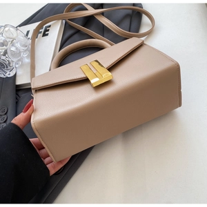 Close-up of khaki textured leather handbag with a gold metal lock and minimal design
