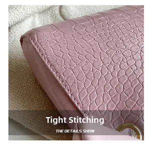 Close-up of pink crocodile texture leather with tight stitching and gold metal eyelet