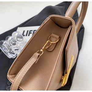 Detailed macro of khaki lychee grain leather handbag with gold metal clasp and stitching