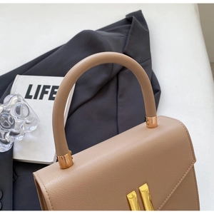 Close-up of pebble leather texture and gold metal hardware on crossbody handbag