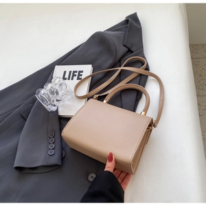 Detail of beige textured leather handbag featuring elegant gold metal hardware connections