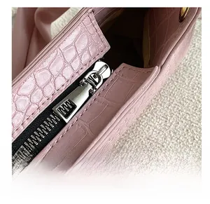 Close-up of smooth silver metal zipper on pink crocodile pattern leather bag detail