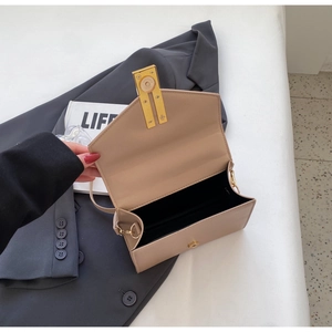 Close-up of light khaki crossbody bag with gold buckle and magnetic flap closure