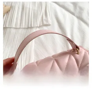 Detail of pink quilted leather handbag featuring a curved handle and gold hardware accents