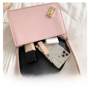 Macro view of a small pink crossbody bag showing spacious interior with essential items